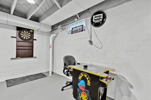 A room with a dartboard, a Jeep sign, and a Pac-Man arcade machine. - Peaceful Hideaway Perfect For Extended Stays (Indianapolis)