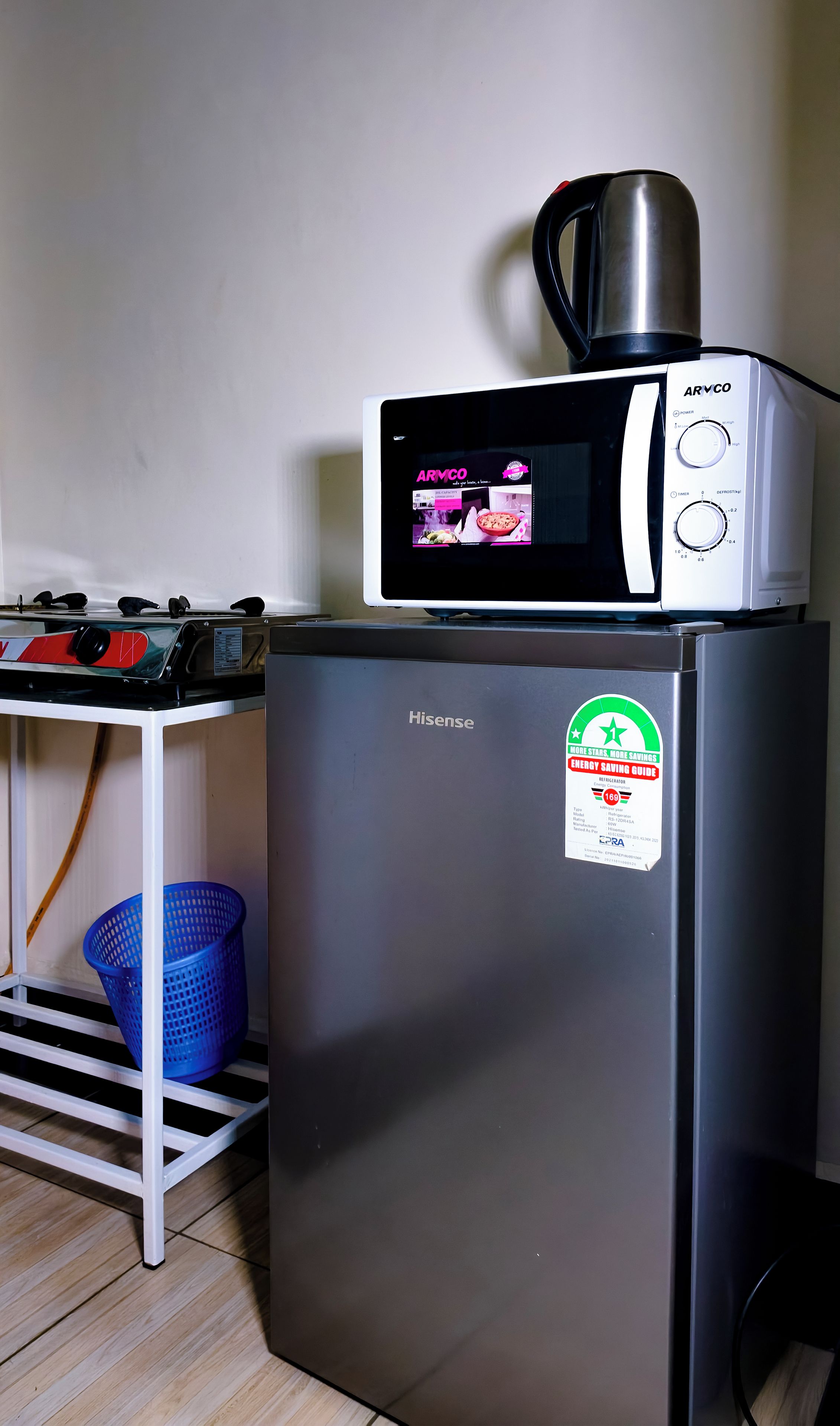 A compact kitchen with a Hisense refrigerator, a microwave, and a small table with a kettle.