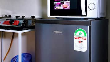 A compact kitchen with a Hisense refrigerator, a microwave, and a small table with a kettle.