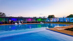 Una piscina con sillas de descanso y una zona de estar cubierta.