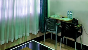 Ein Zimmer mit Deckenventilator, Tisch und Stühlen, einer Wasserflasche und einem Telefon.
