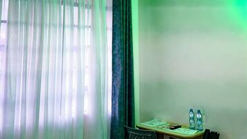 A room with a ceiling fan, a table with chairs, a water bottle, and a phone.