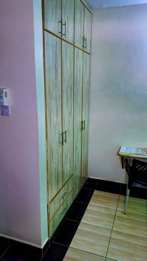 Una habitación con armario, una mesa y una silla, y piso de baldosas.