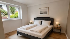 A bedroom with a bed, bedside tables, a window, and a ceiling light. - The Golden Sunset Villa Wiesbaden (Schlangenbad)
