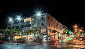 A hotel with a prominent sign, a parking area, and a street with streetlights. - HOTEL JUAN MARIA (Tuluá)