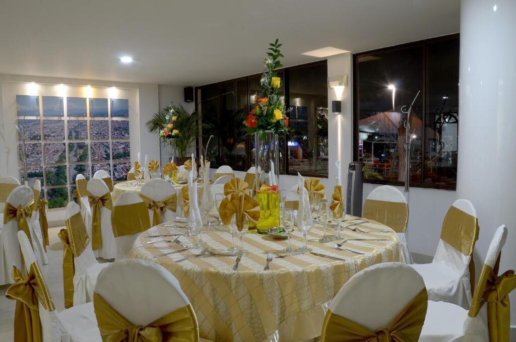 A banquet hall with round tables, white and gold chairs, and floral centerpieces.
