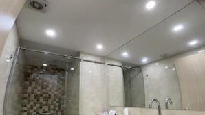 Un baño moderno con ducha acristalada, inodoro, lavamanos y espejo.