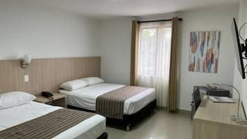 Una habitación de hotel con dos camas, un escritorio, una silla y un ventanal con cortinas.