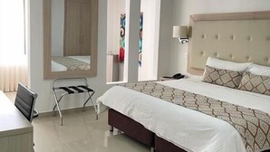 Una habitación de hotel con cama, escritorio, silla, espejo y armario.