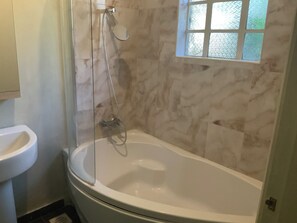 A bathroom with a glass-enclosed shower, a white bathtub, and a window with a view. - Adorable 2-bedroom bungalow in Nairobi perfect for relaxing stays (Nairobi)
