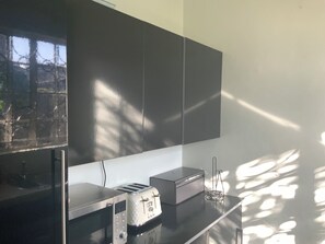 Une cuisine équipée d’un four à micro-ondes, d’un grille-pain et d’un placard.