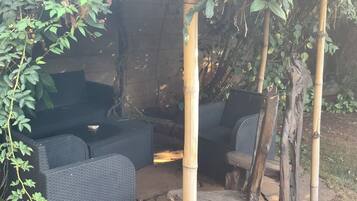 An outdoor seating area with wicker furniture and a bamboo structure.