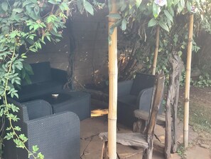 Un espace extérieur aménagé avec des meubles en osier et une structure en bambou.