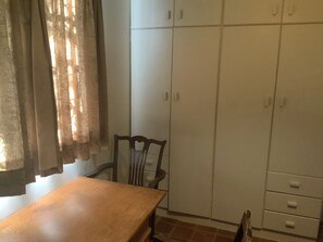 A room with a wooden table, a chair, and a wardrobe with multiple doors.