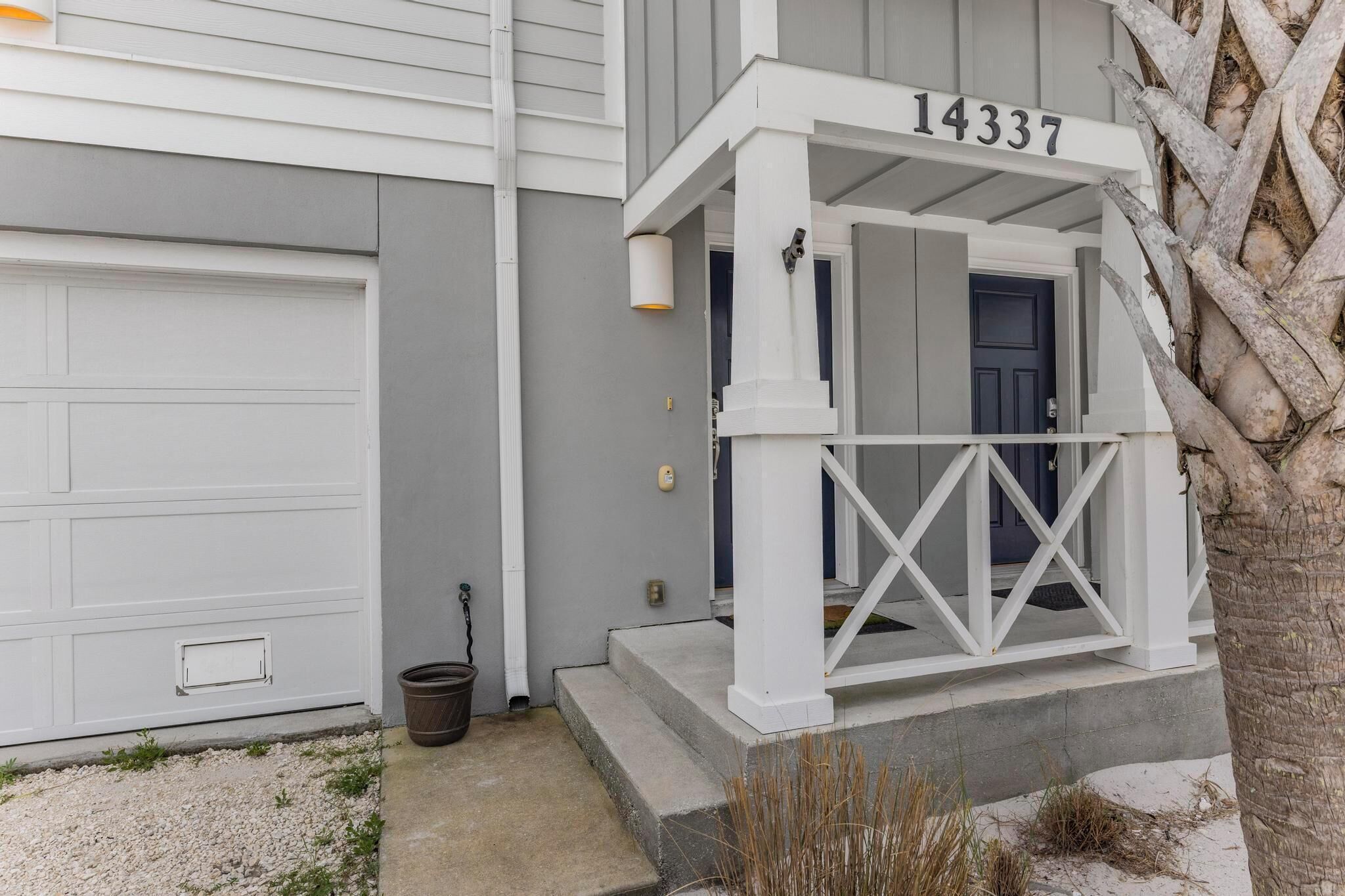 A residential house with a garage, a porch with a railing, and a mailbox.