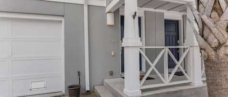 A residential house with a garage, a porch with a railing, and a mailbox.