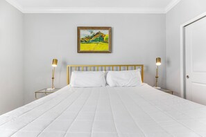 A hotel room with a large bed, two bedside tables with lamps, a painting on the wall, and a door. - 🐾 Supplication | Pet Friendly Townhome at Lost Key Golf and Beach Club (Perdido Key)