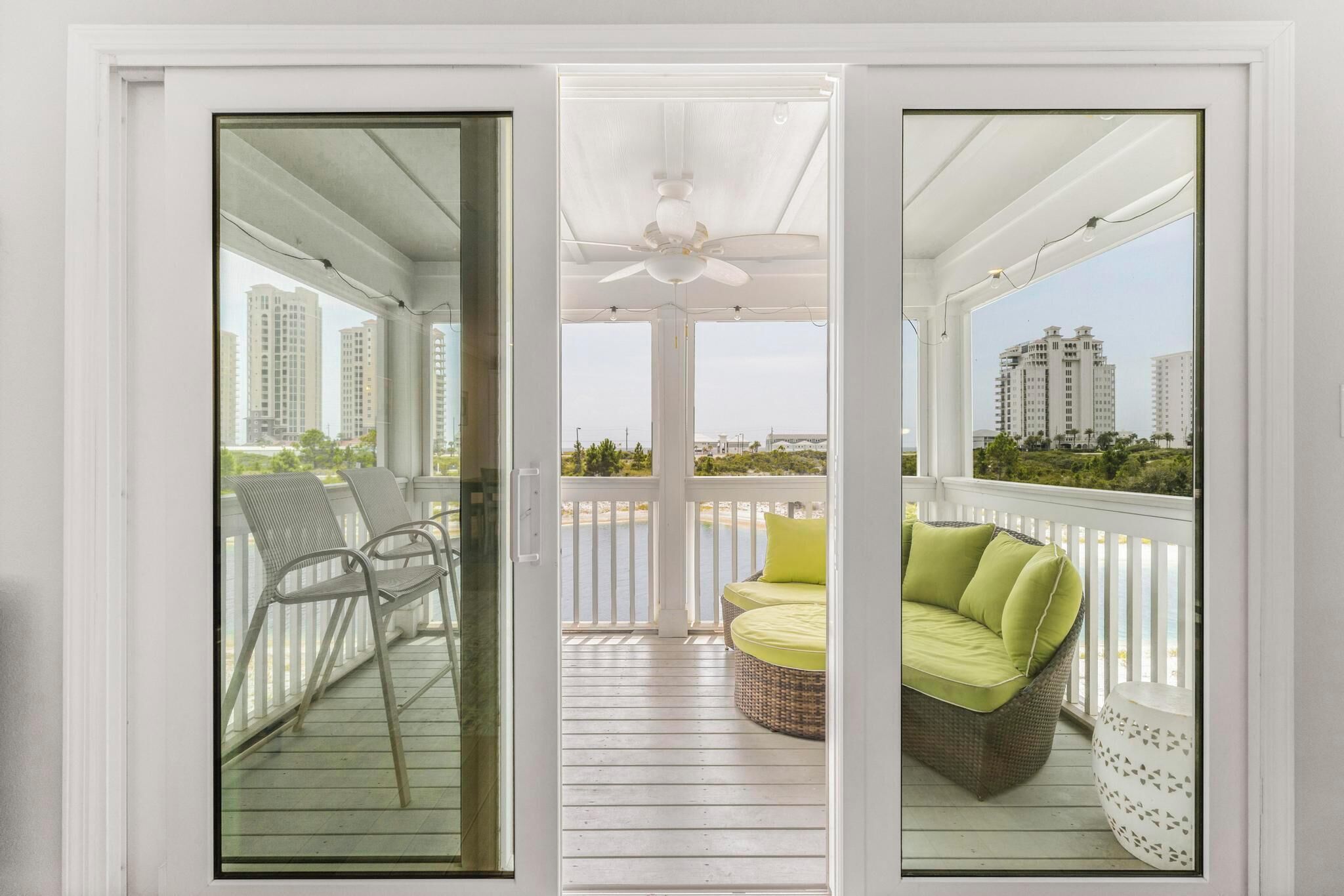 A balcony with a white ceiling fan, wicker furniture, and a view of the cityscape.