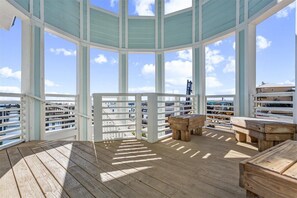 En takterrass med tak, utemöbler i trä och utsikt över staden.