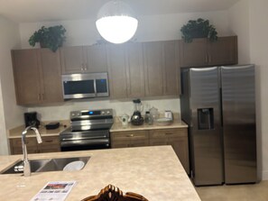 A kitchen with stainless steel appliances, wooden cabinets, a built-in oven, and a refrigerator. - Enjoyable 5-bedroom house with AC in charming Naples (Naples)