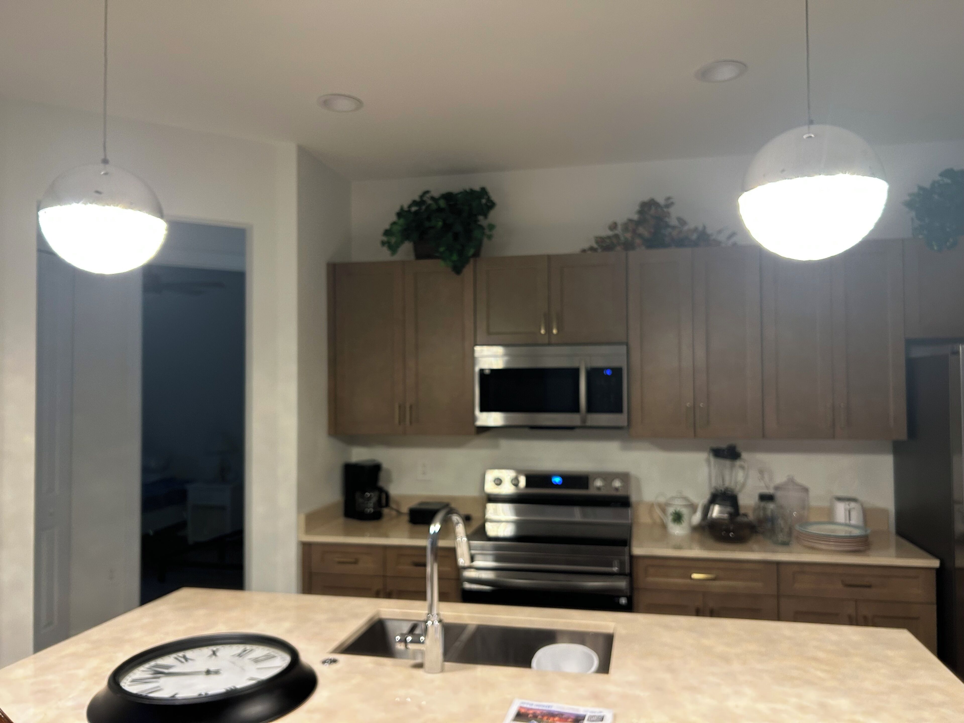 A modern kitchen with stainless steel appliances, a central island with a sink, and pendant lighting.