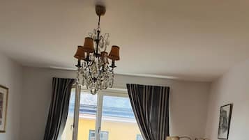 Un salón con sofá, una mesa de centro, televisor, candelabro y vistas a edificios.