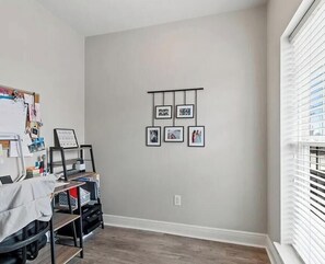 A room with a bulletin board, framed pictures, a desk with a chair, and a window with blinds. - Spacious game weekend 3-bedroom condo in adorable Tuscaloosa. (Tuscaloosa)