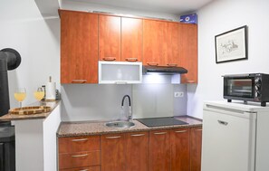 Cocina compacta con armarios de madera, microondas y fregadero.