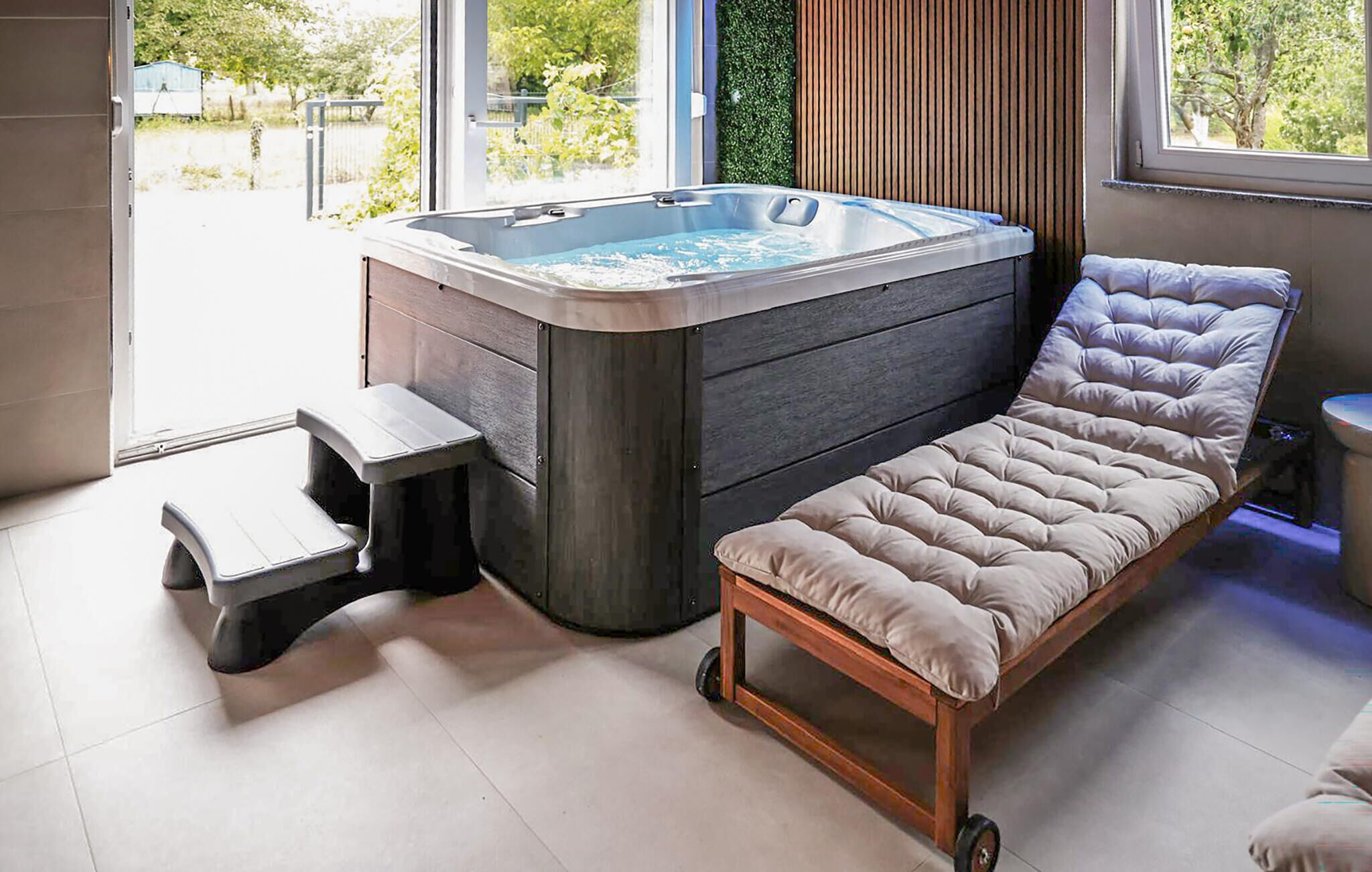 A modern bathroom with a hot tub, a step stool, and a cushioned chair.