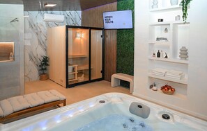 Uma sala de spa moderna com hidromassagem, área de chuveiro com box de vidro e prateleiras com artigos de higiene.