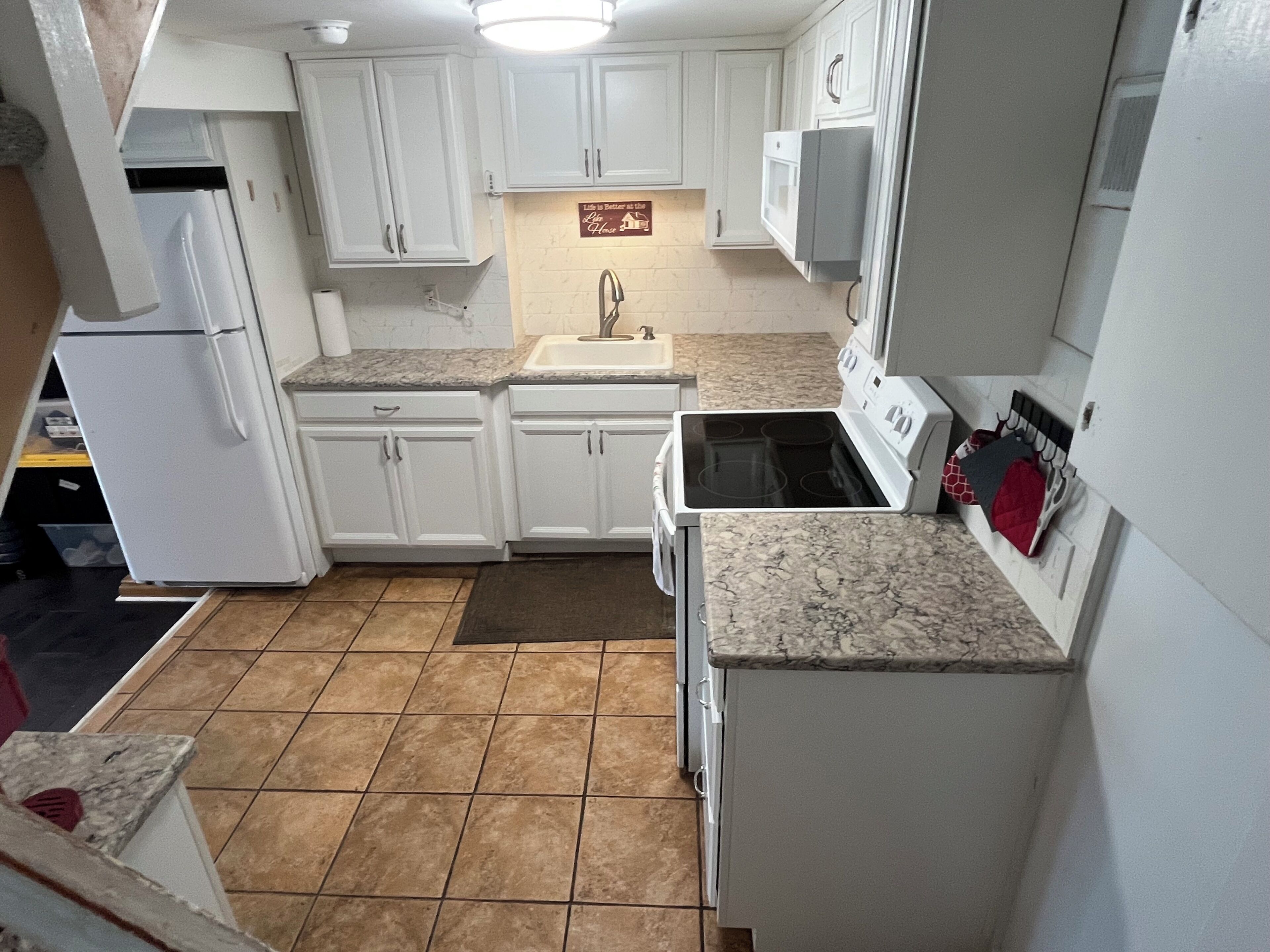 A kitchen with white cabinets, a stove, a refrigerator, and a microwave.