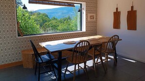Ein Essbereich mit großem Fenster, Holztisch und Stühlen.