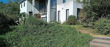 Une maison moderne à deux étages, dotée d’un toit plat, de grandes fenêtres et d’un porche abrité.