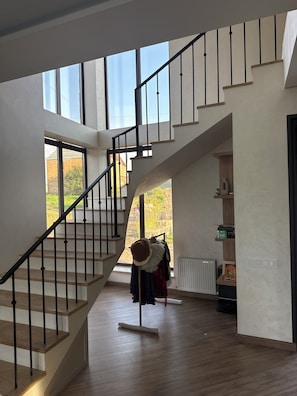 A modern interior with a staircase, large windows, and a view of the outdoors.