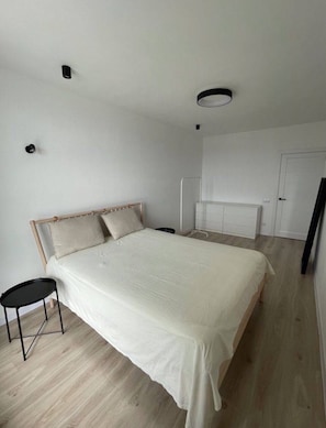 A bedroom with a bed, a bedside table, a wardrobe, and a door.