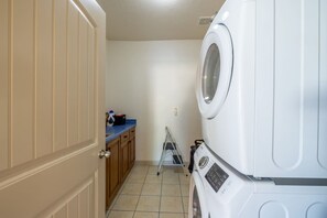 A laundry room with a washing machine, a dryer, a blue countertop, and a wooden cabinet. - Relocation Home | Workspace, Garage, Elevator, W&D (North Salt Lake)