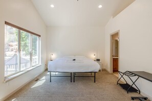 Une chambre à coucher avec un lit, des lampes de chevet, un bureau et une fenêtre.