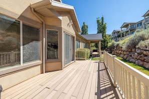 Une terrasse en bois avec un muret de soutènement en pierre et un espace salon abrité.