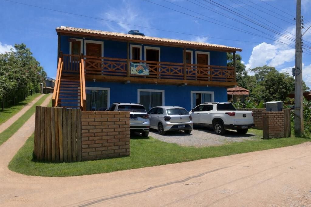 A two-story building with a balcony, a staircase, and a parking area with three vehicles.