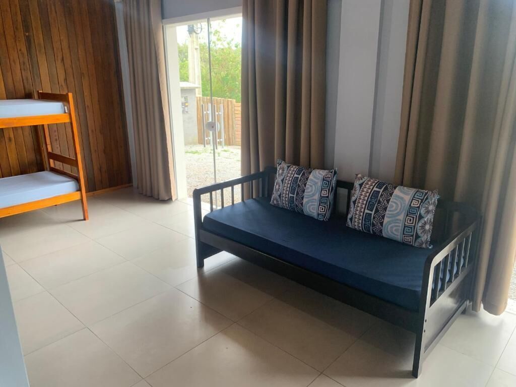 A room with a sofa, a wooden bunk bed, and a sliding glass door leading to an outdoor area.