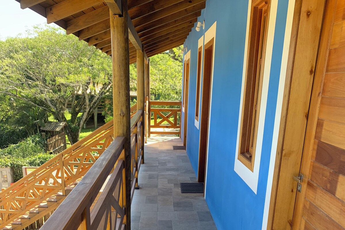 A corridor with a wooden railing, tiled flooring, and doors leading to rooms.