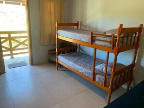 A bunk bed with a lower bunk, a door leading outside, and a window with curtains.