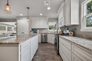 A kitchen with white cabinets, granite countertops, stainless steel appliances, and pendant lighting. - F'burg Wine Trail HQ 2BR Dog Friendly | Patio (Fredericksburg)