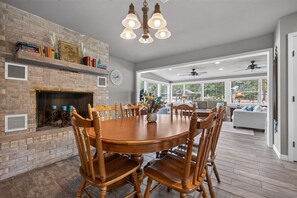 Un comedor con chimenea de ladrillo, sillas de madera y candelabro.
