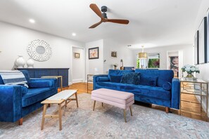 Ein modernes Wohnzimmer mit einem blauen Sofa, einer hölzernen Bank und einem Deckenventilator.