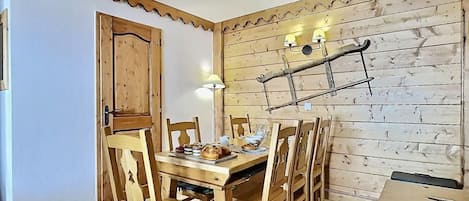 Ein Essbereich mit einem Holztisch und -stühlen, einer rustikalen Wand mit einer Leiter und einer Tür mit Holzrahmen.