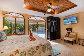 A bedroom with a large bed, a ceiling fan, a TV, and a view of the outdoors. - Jungle Pool Villa - 5BR Gated Playacar Hideaway (Playa del Carmen)