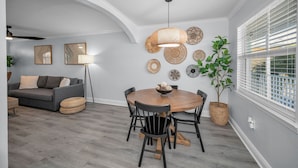 Ein Essbereich mit einem runden Holztisch, schwarzen Stühlen und einer hängenden Lampenschirm aus Gewebe.