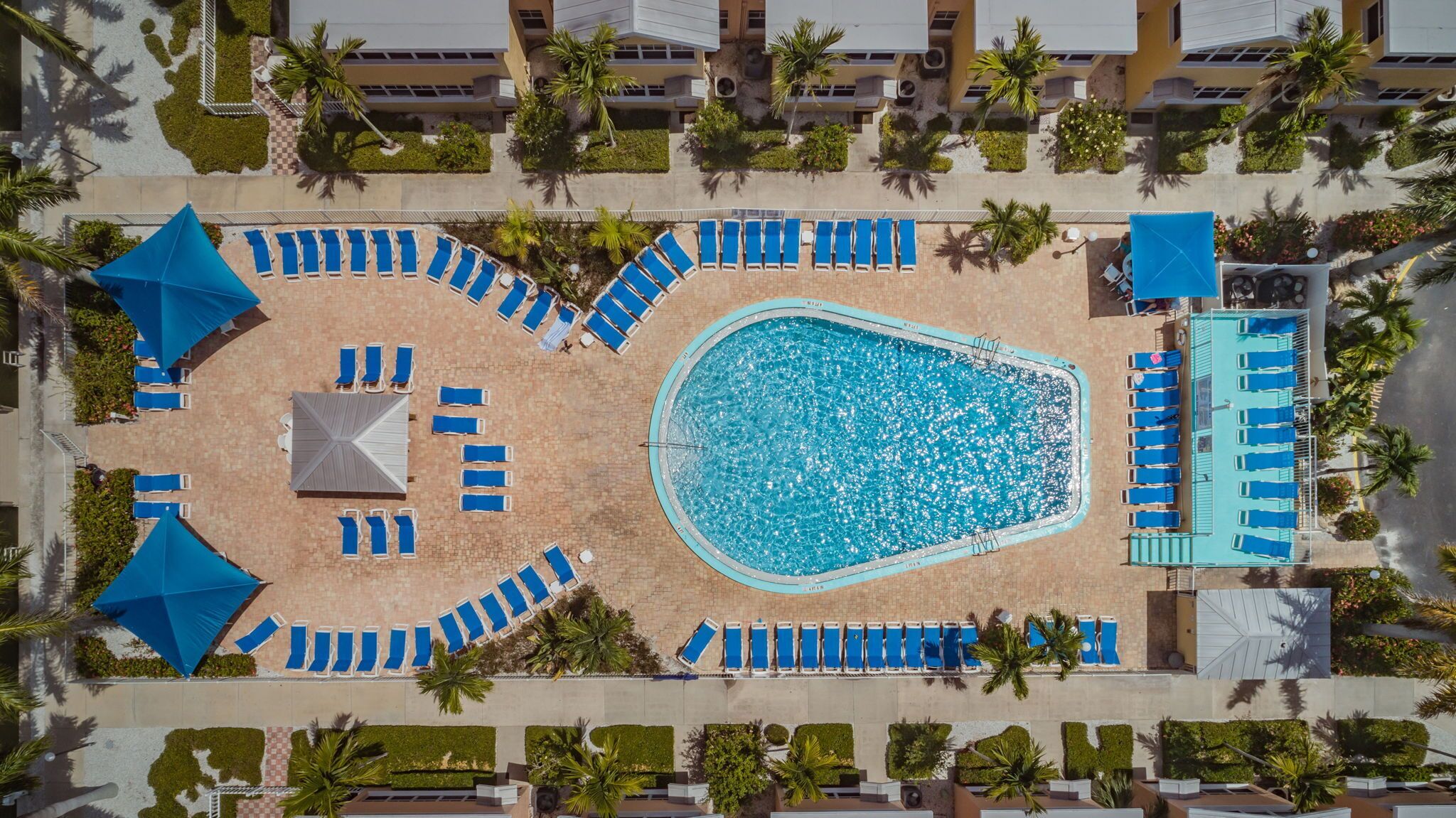 Vue aérienne d’un espace piscine d’hôtel, avec de nombreux transats et une piscine centrale.