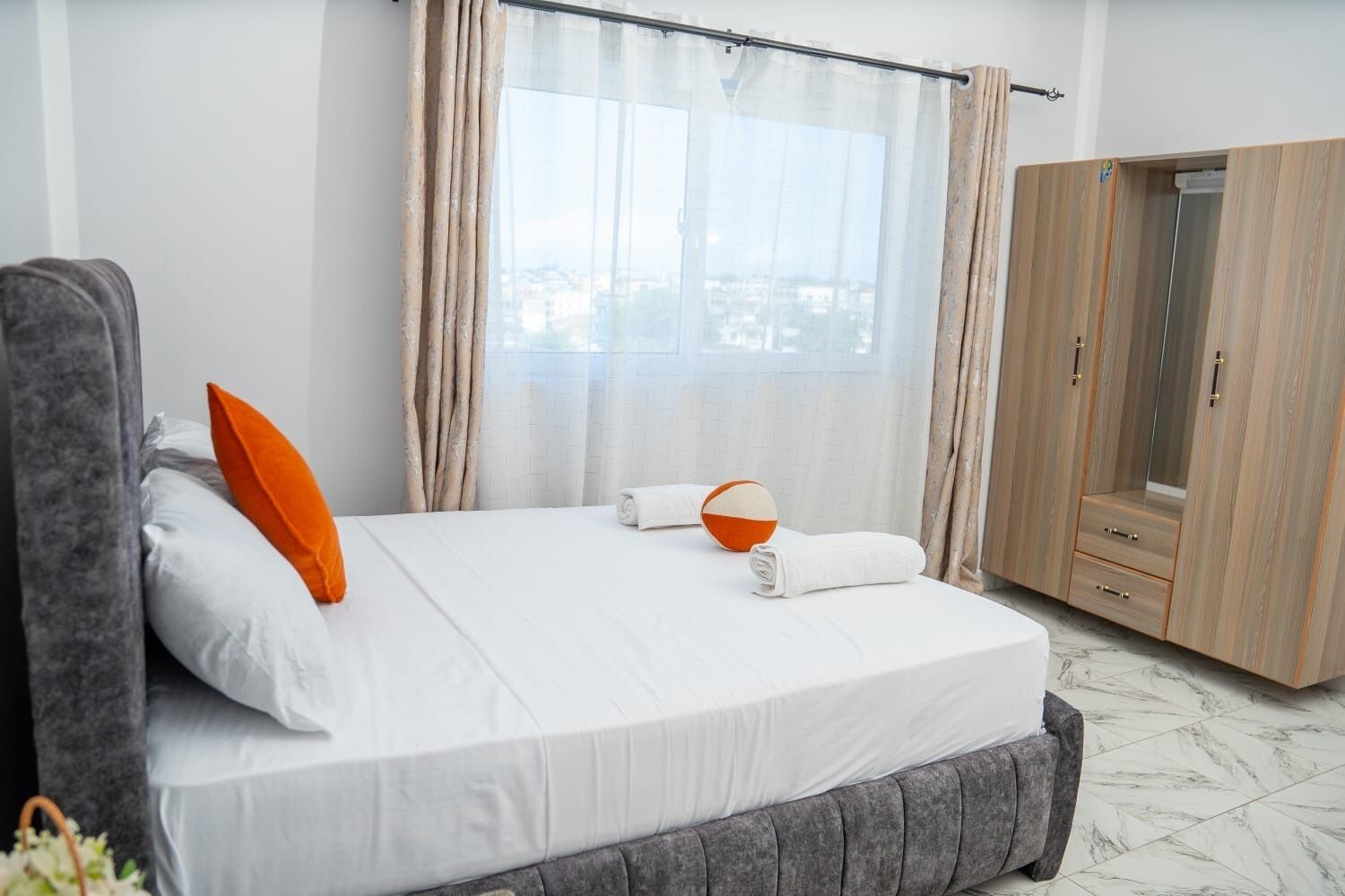 Una habitación de hotel con una cama, un armario y una ventana con cortinas.